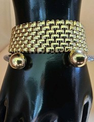 Mixed metal bracelet stack featuring a bold gold tone mesh cuff paired with a…