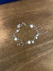 Silver bracelet with multiple coloured and silver pendants of different shapes.