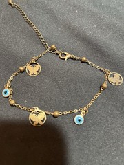 gold-tone ankle bracelet featuring blue evil eye charms and butterfly pendants
